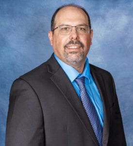 A man in a suit and tie standing next to a wall.